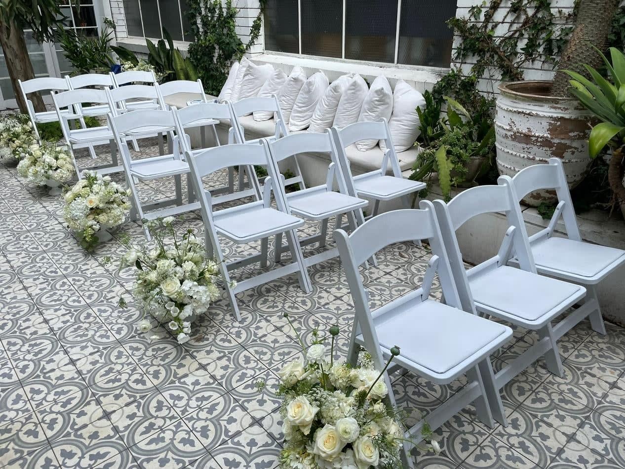 White padded folding chairs set up for a gladiator-themed wedding ceremony.