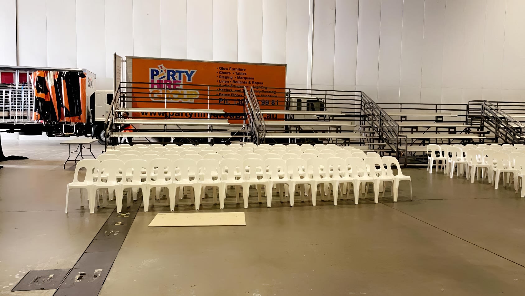 White plastic chairs in a warehouse with a truck in the background.