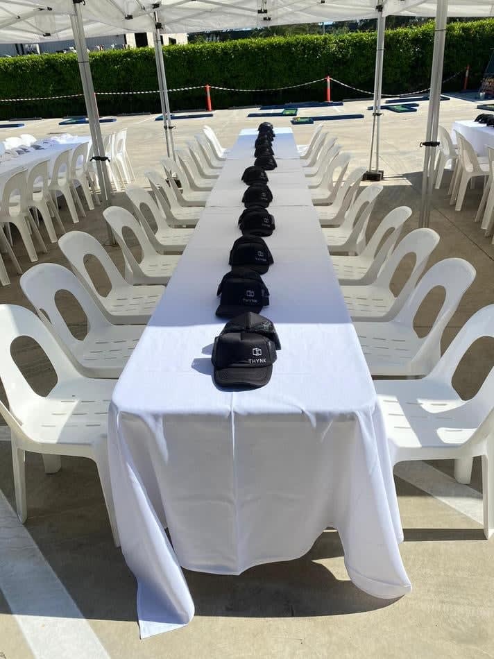 A table set up with white plastic stackable chairs and hats.