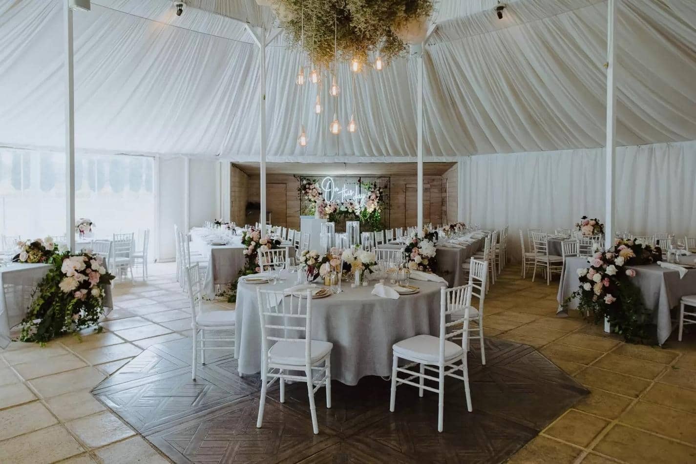 A wedding reception in a white tent with White Tiffany Chair Hire.