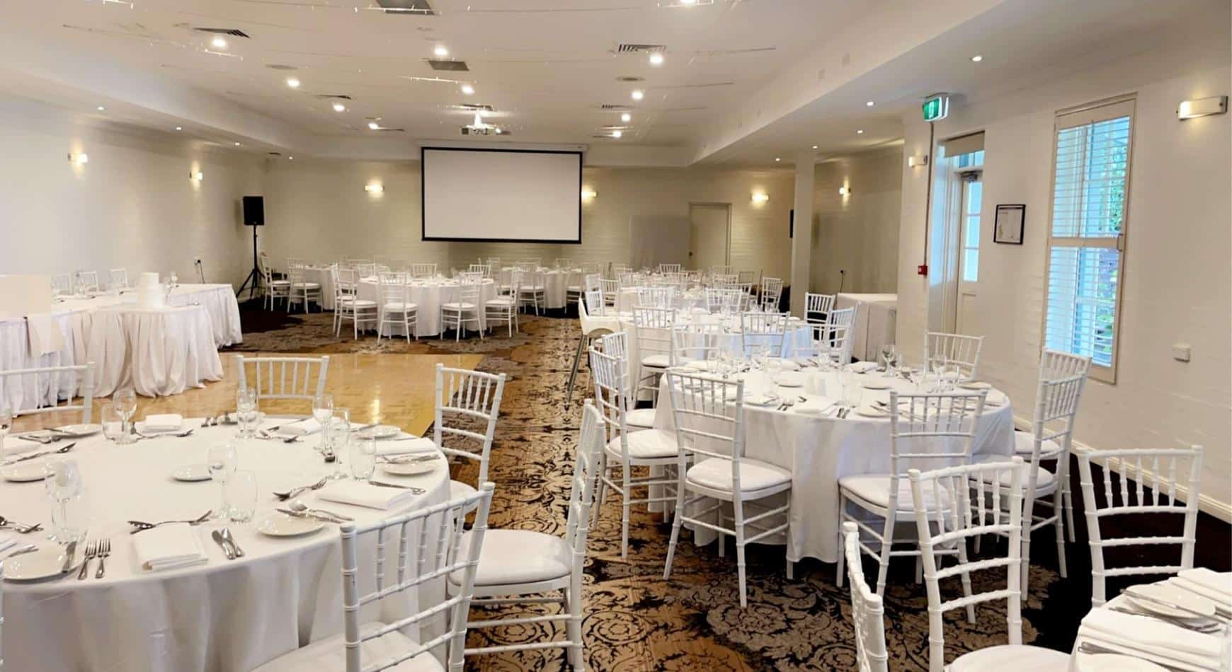 A large room with white tables and chairs available for White Tiffany Chair Hire.