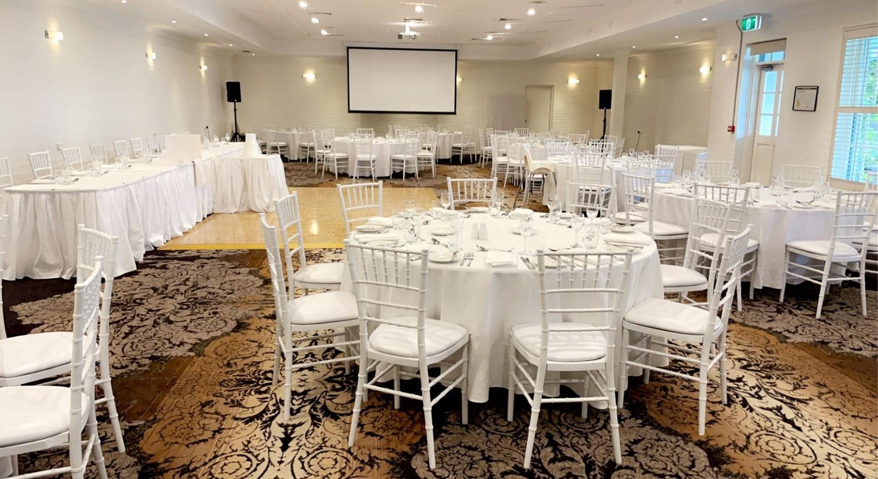 A large room with white tables and White Tiffany Chair Hire.