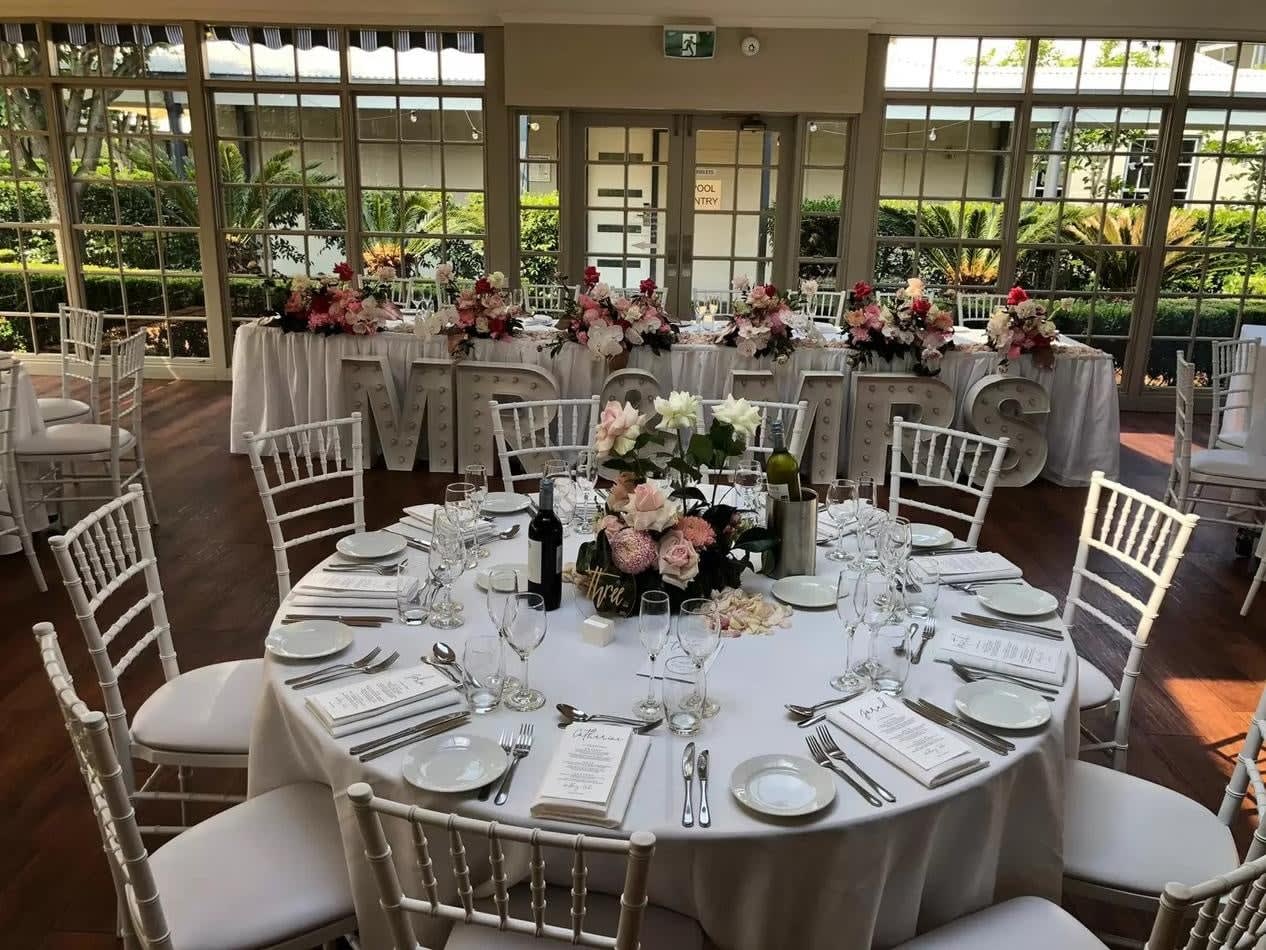 A wedding reception set up with white tables and White Tiffany chair hire.