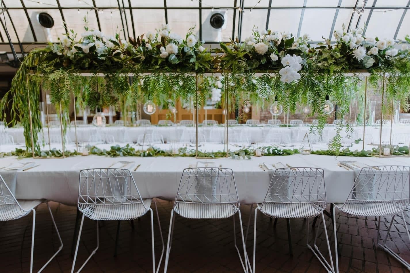 A white table with greenery and White Arrow Chair Hire.