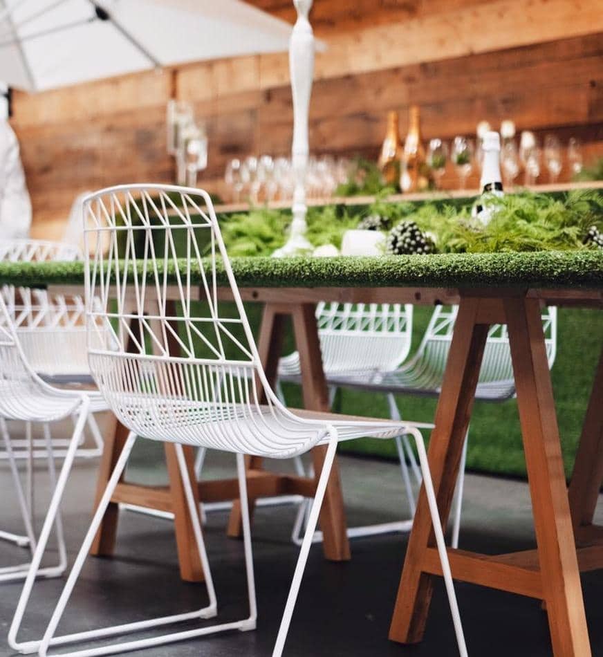 A white table and chairs with green grass in the background.