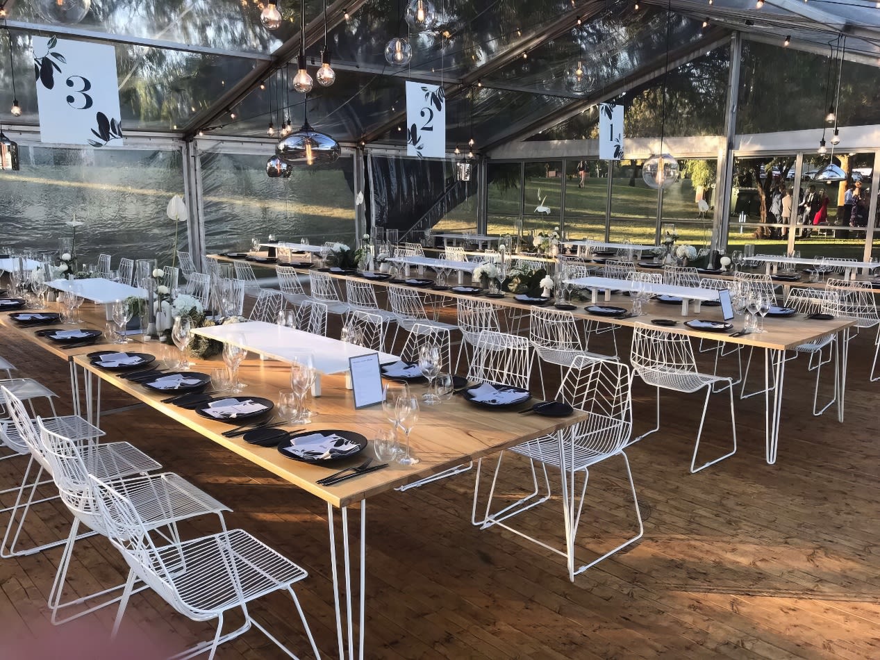 A white tent set up with tables and chairs, including White Arrow Chair Hire.