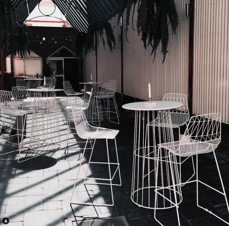 A white table and chairs in a courtyard, available for White Stool Hire.