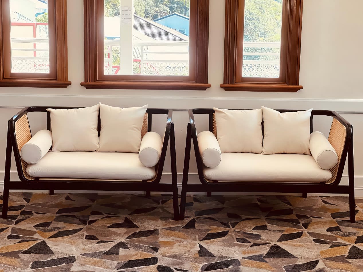 Two black rattan lounge chairs in front of a window.