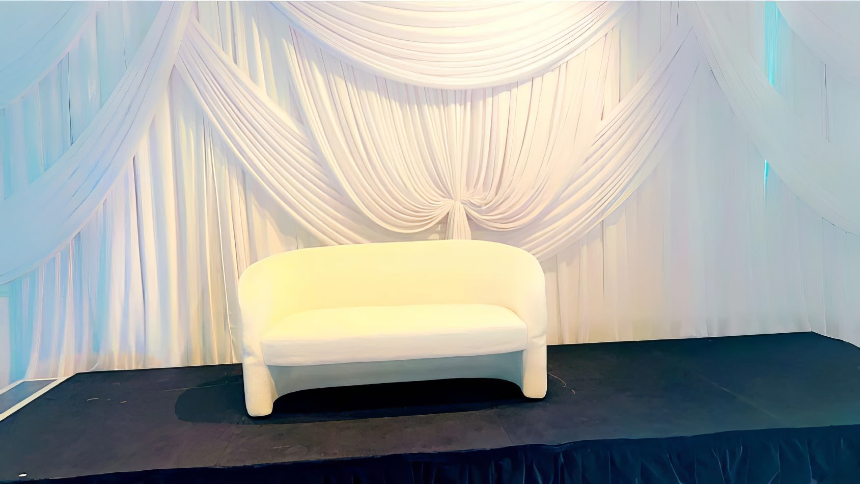 A white chair in front of a white backdrop, available for Bouclé 2 Seater Sofa Lounge Hire.