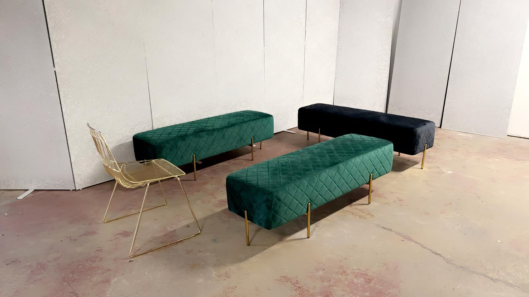 Three emerald green and gold ottoman benches in a room.