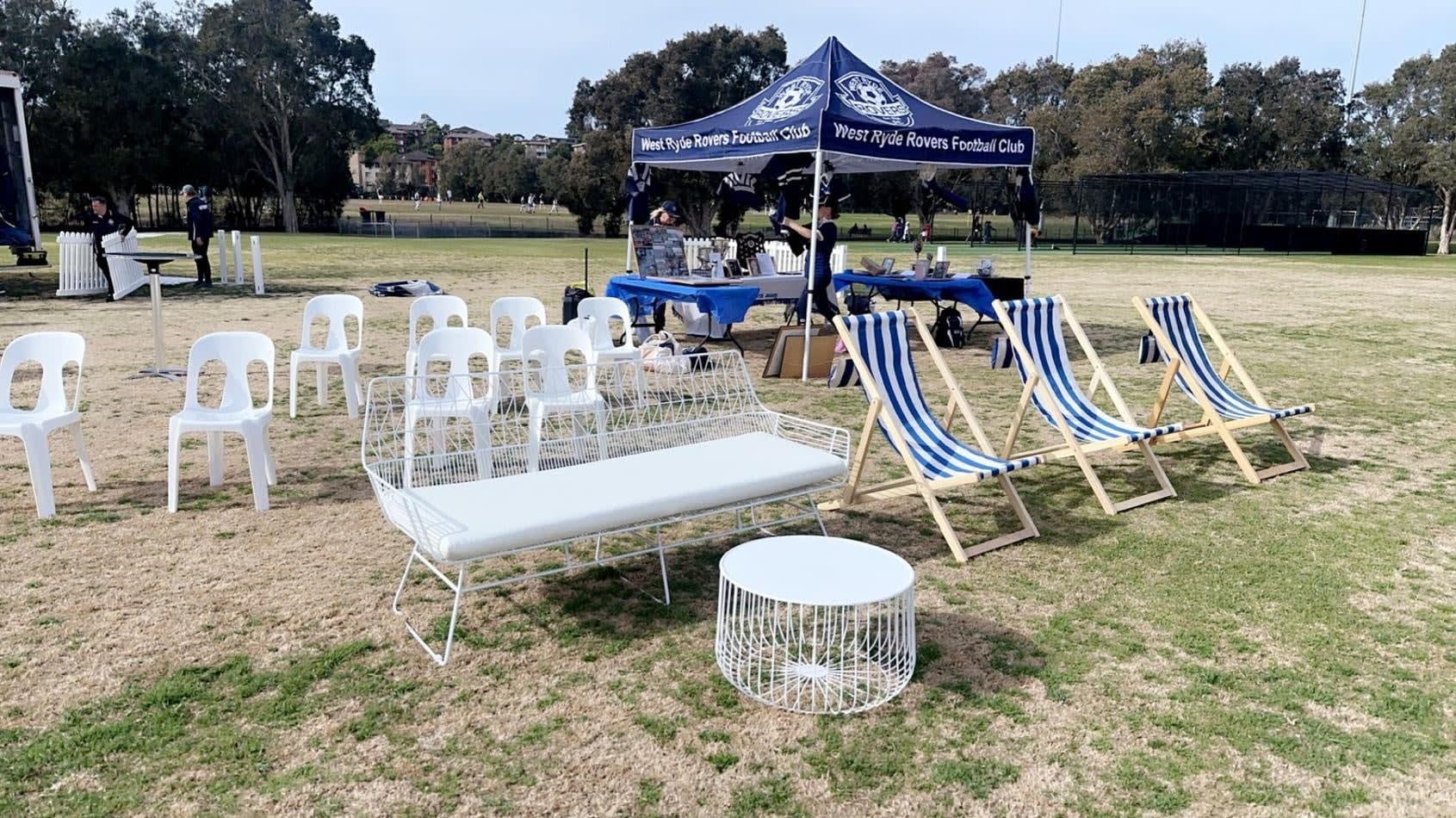 A group of white chairs and tables on a grassy field.