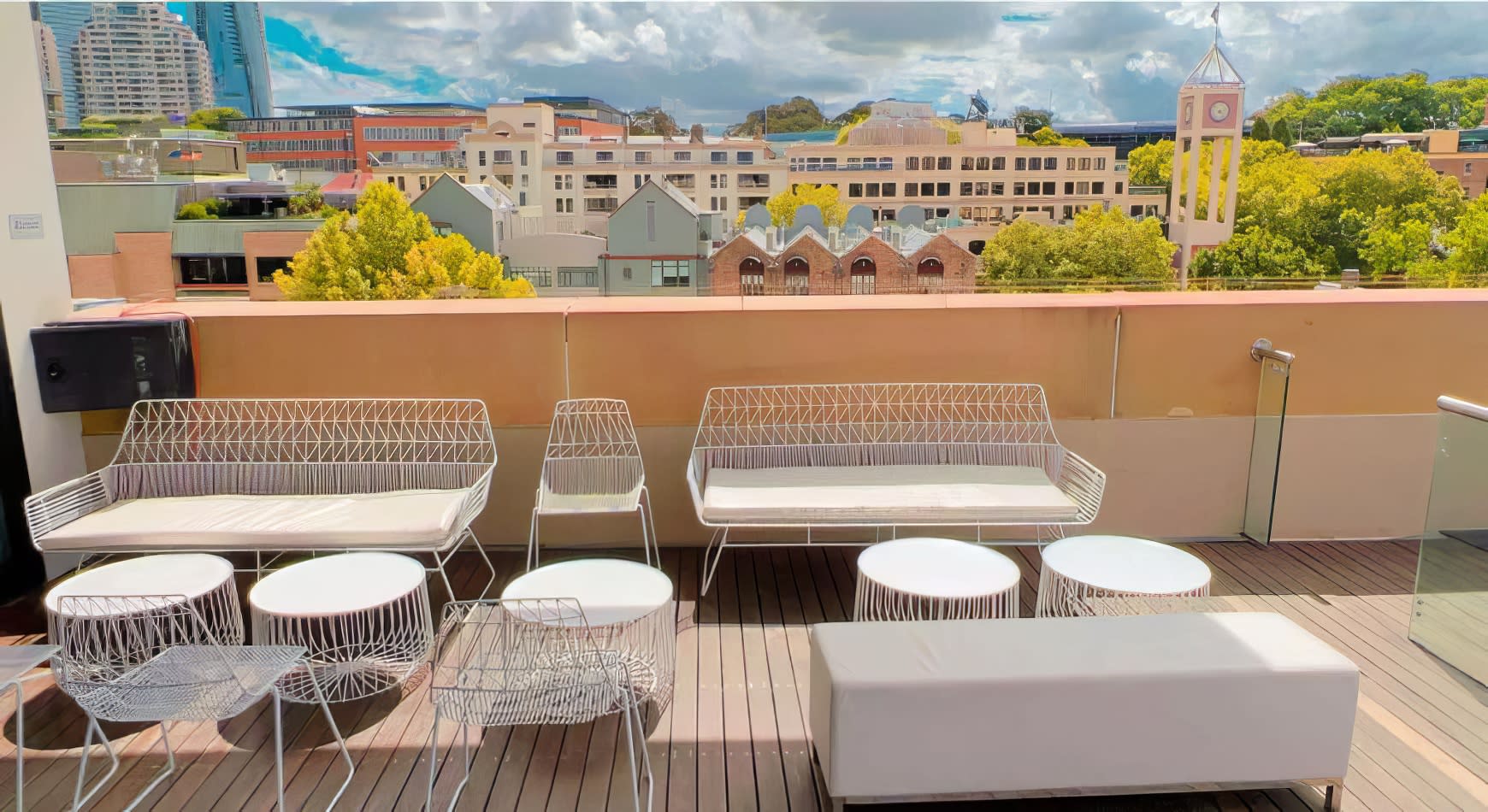 A balcony with white furniture, including a White Arrow 3 Seater Lounge Hire, and a view of the city.
