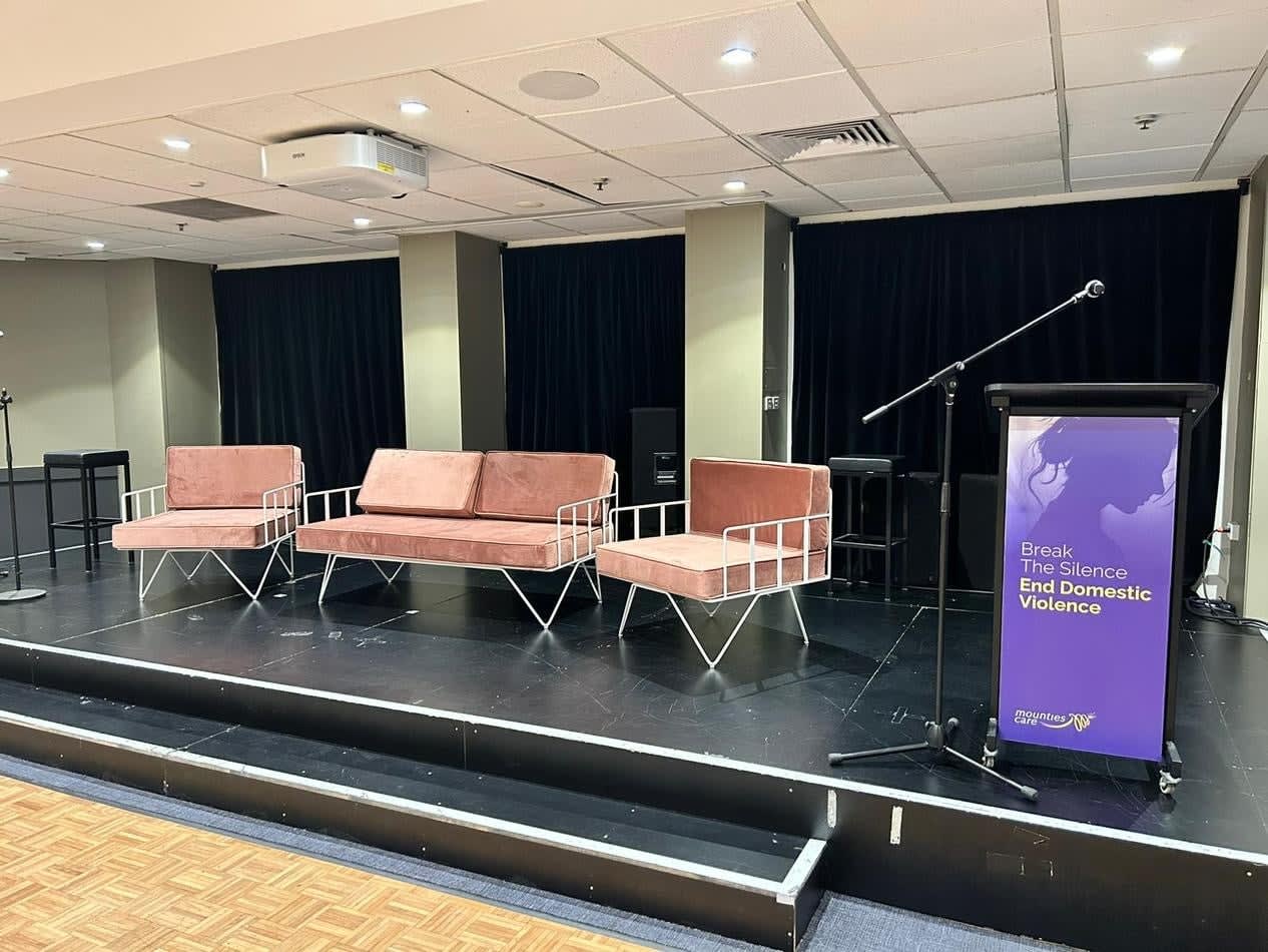 A stage set up with chairs and a podium, adorned with pink velvet cushions.