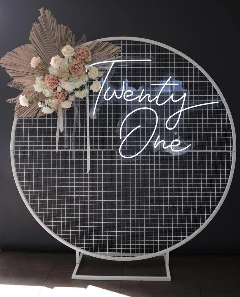 A circular frame with the word twenty one on it, placed against a white mesh backdrop.