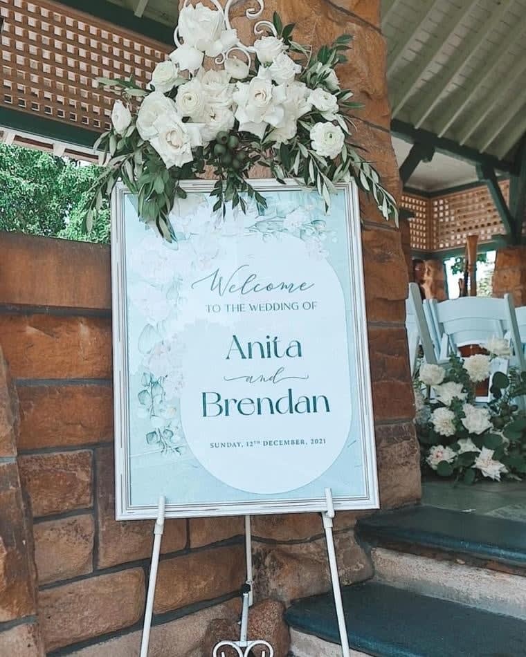 A sign with a white flower arrangement in front of it, available for White French Easel Hire.