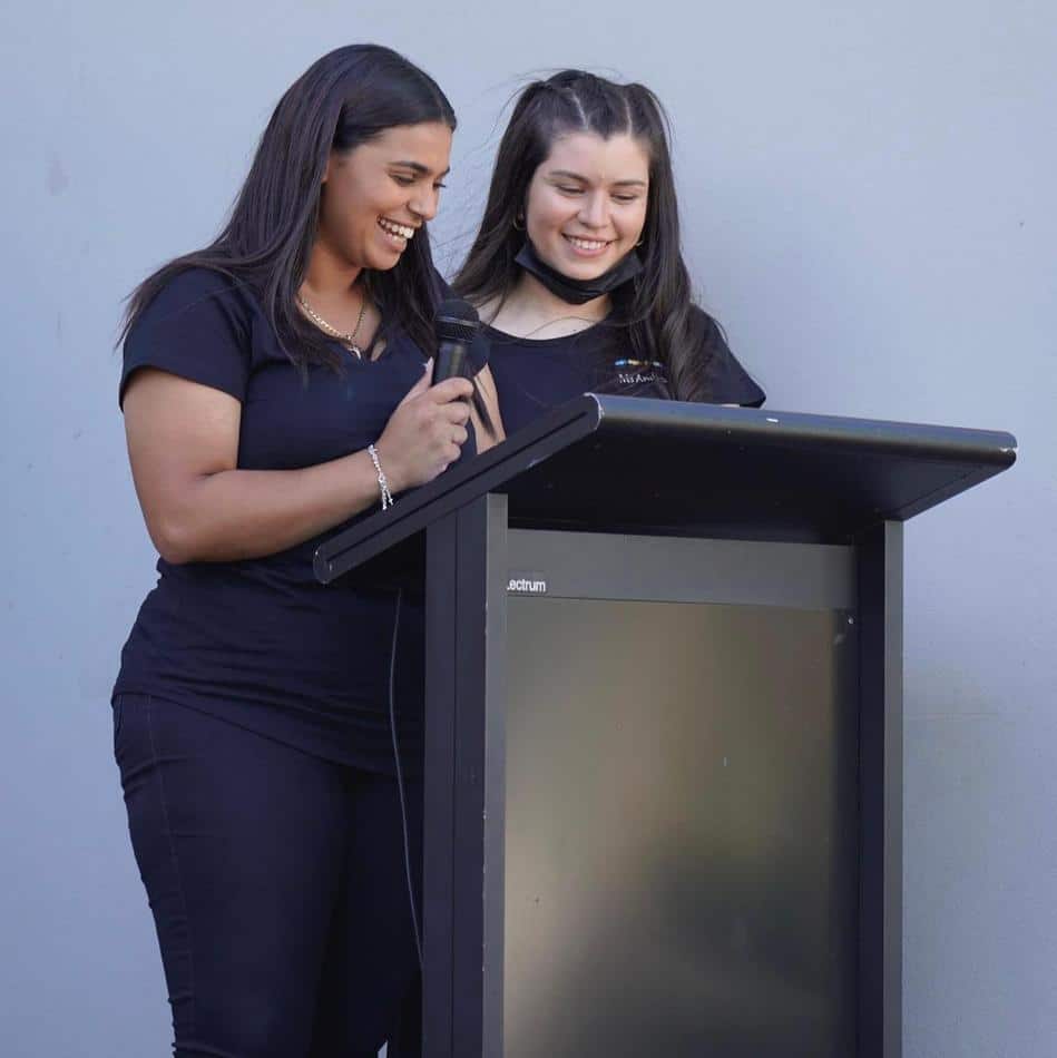 Two women standing in front of a lectern.