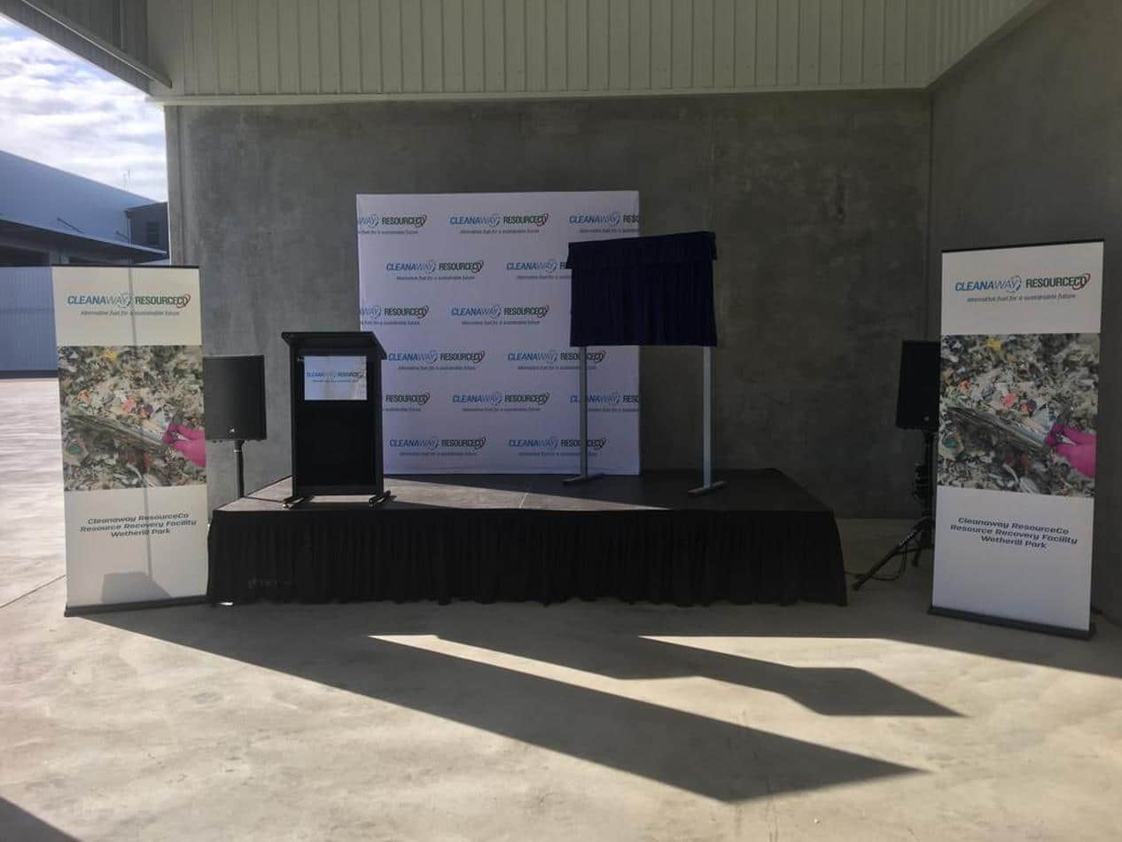 A lectern hire stage set up in front of a large warehouse.