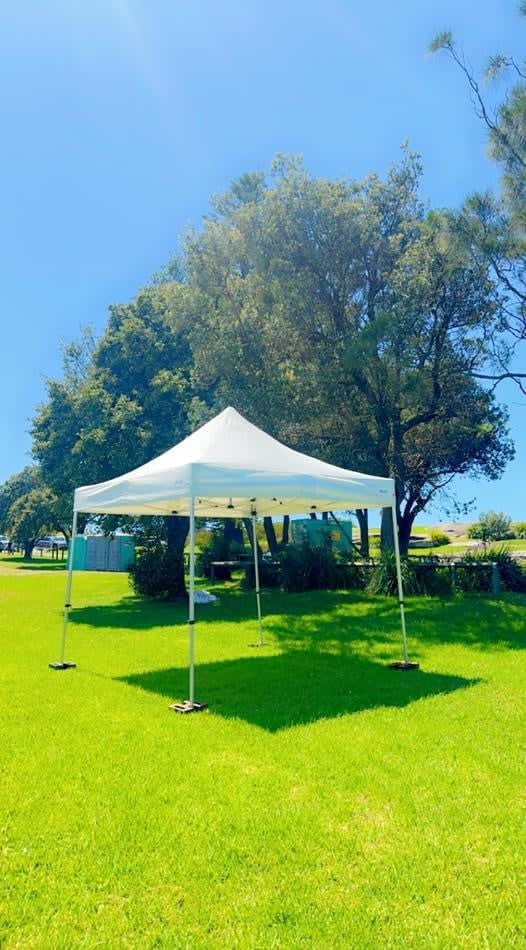 A 3mx3m white tent set up in a grassy field.