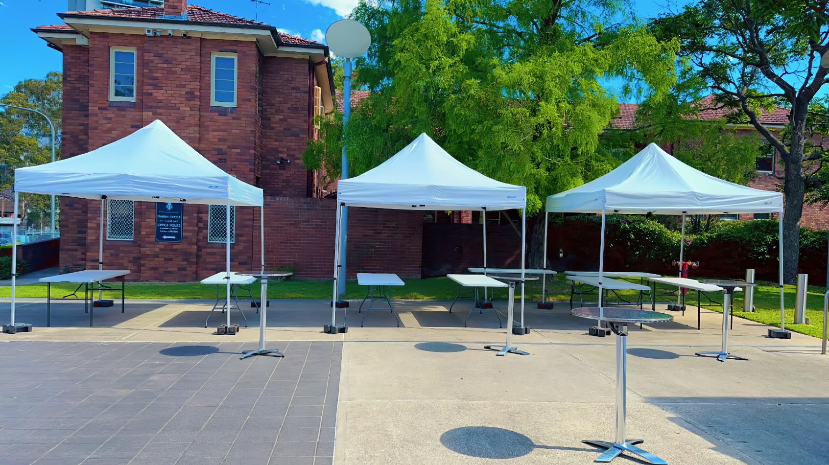 Four 3mx3m Pop Up Marquees with White Roofs set up in front of a brick building.