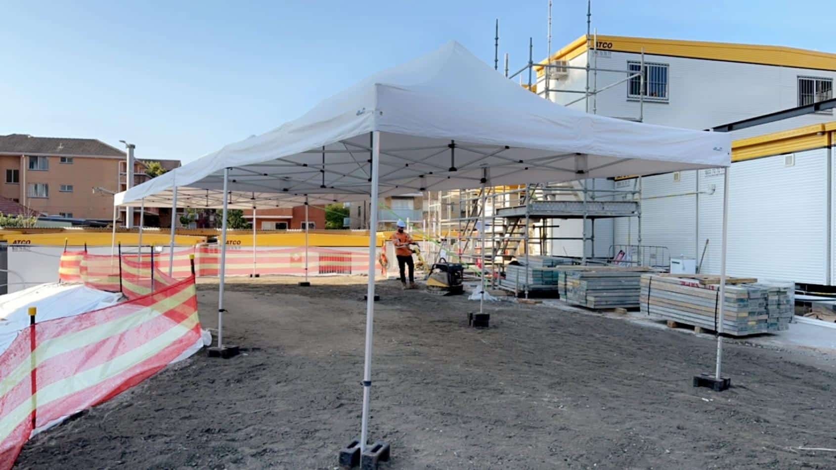 A 4mx8m Pop Up Marquee with a white roof is being set up in front of a building.