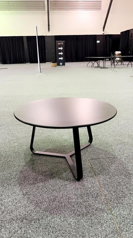 A black round coffee table in a large conference room.