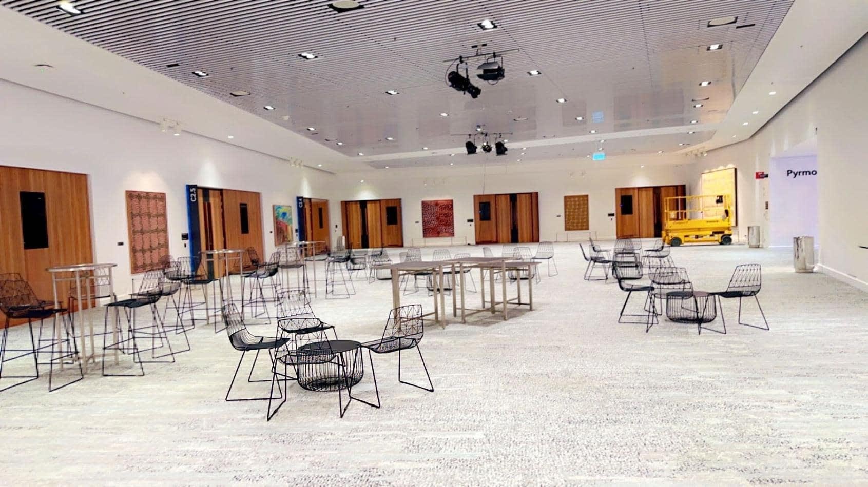 A spacious room with tables and chairs in it, where you can hire black wire coffee tables.