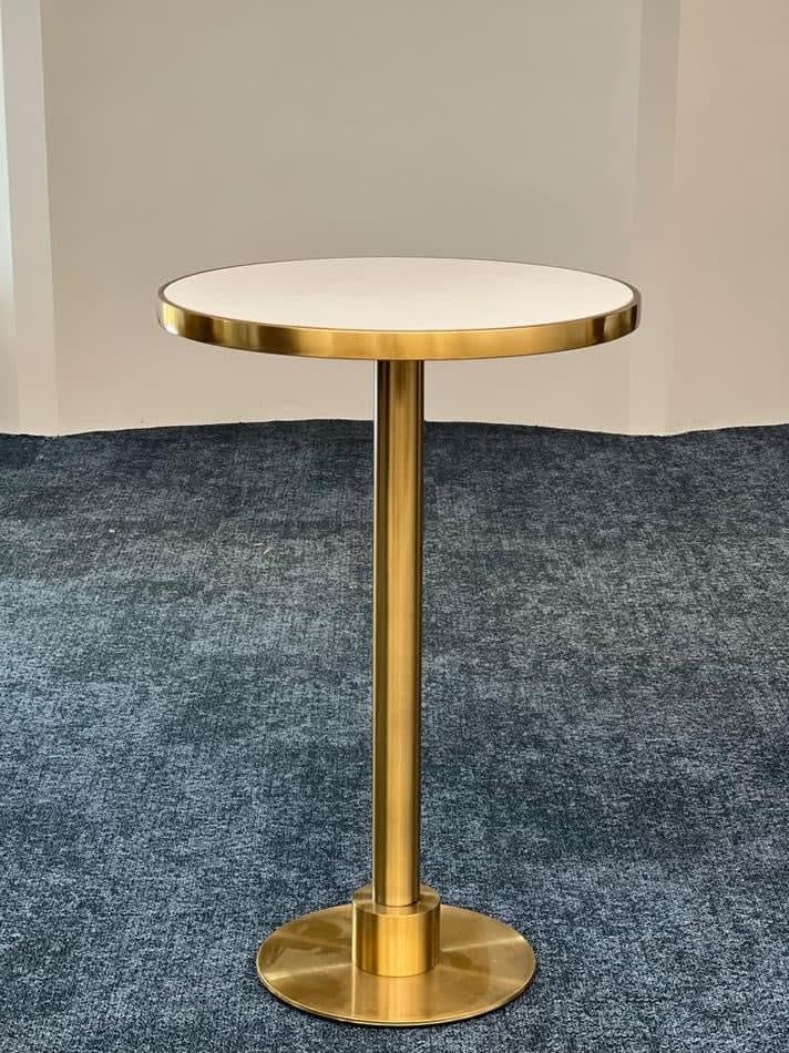 A brass cocktail bar table hire with a white top.