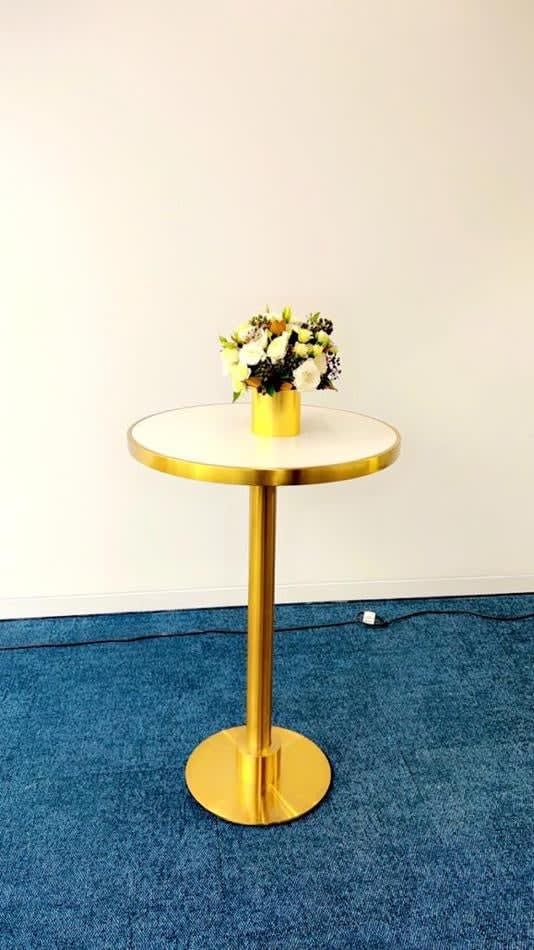 One of our brass cocktail bar tables with a vase of flowers on it