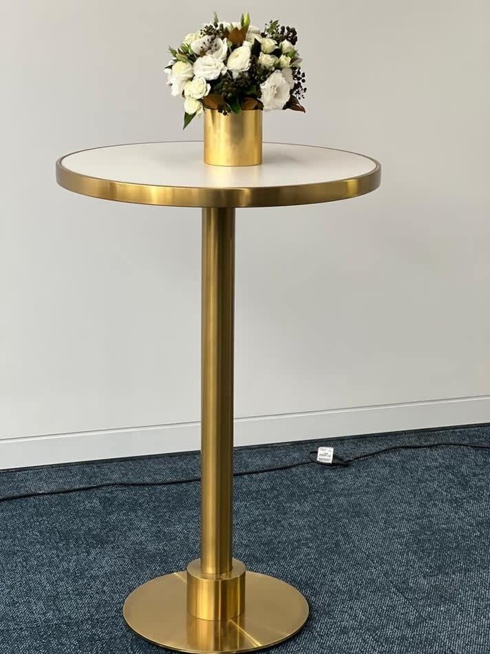 A round brass table with flowers in a vase.