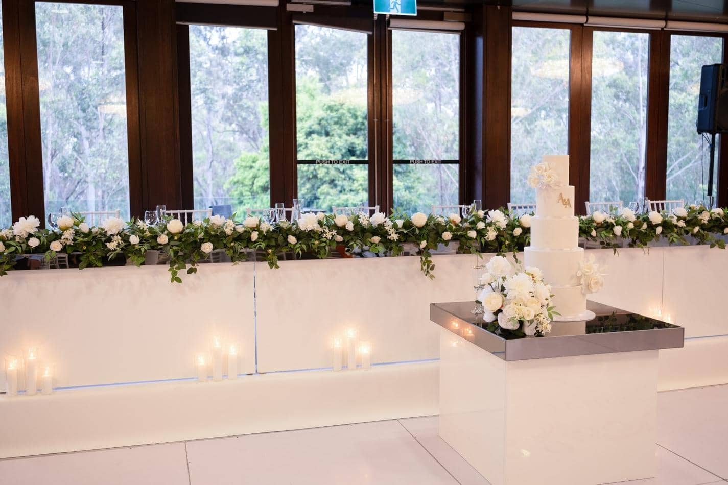 A Gloss Bridal wedding reception with white flowers and candles on a table.