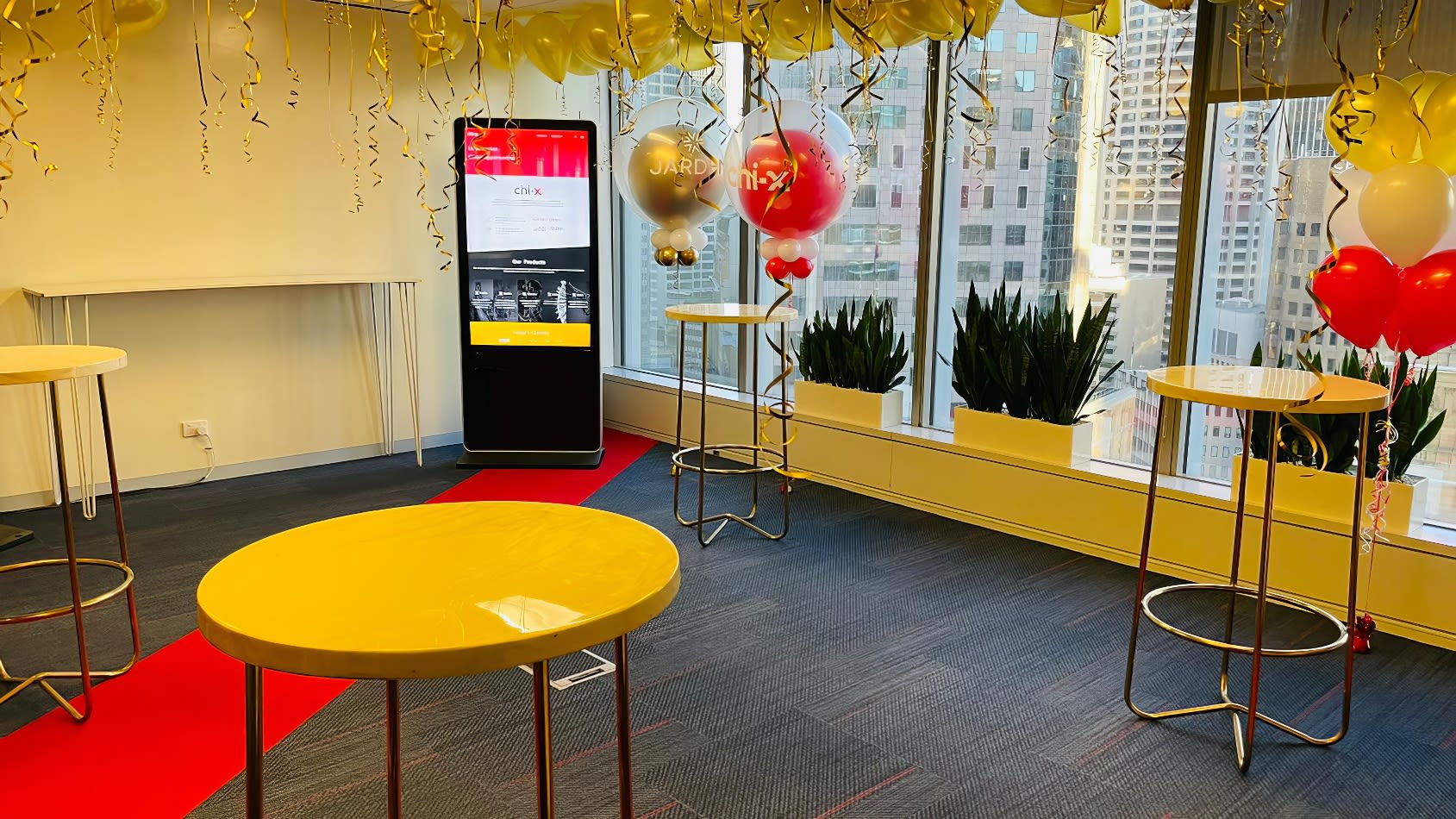 An office with red and yellow balloons and tables adorned with gold wire arrow table with marble top hire.