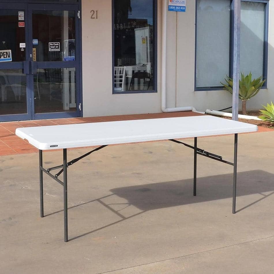 A white plastic trestle table in front of a building.