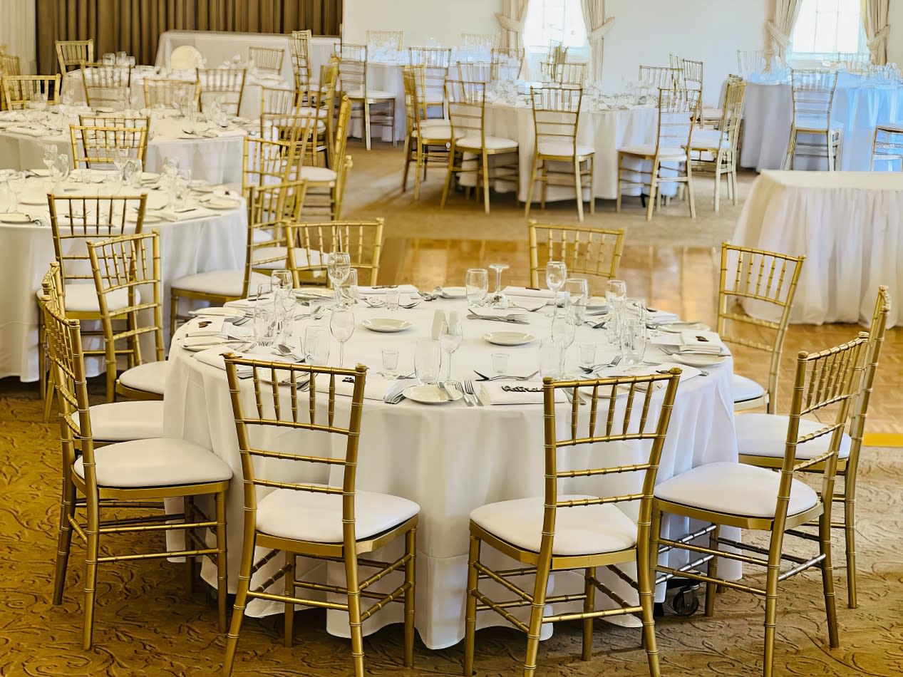 A spacious room furnished with round timber banquet tables and chairs for hire.