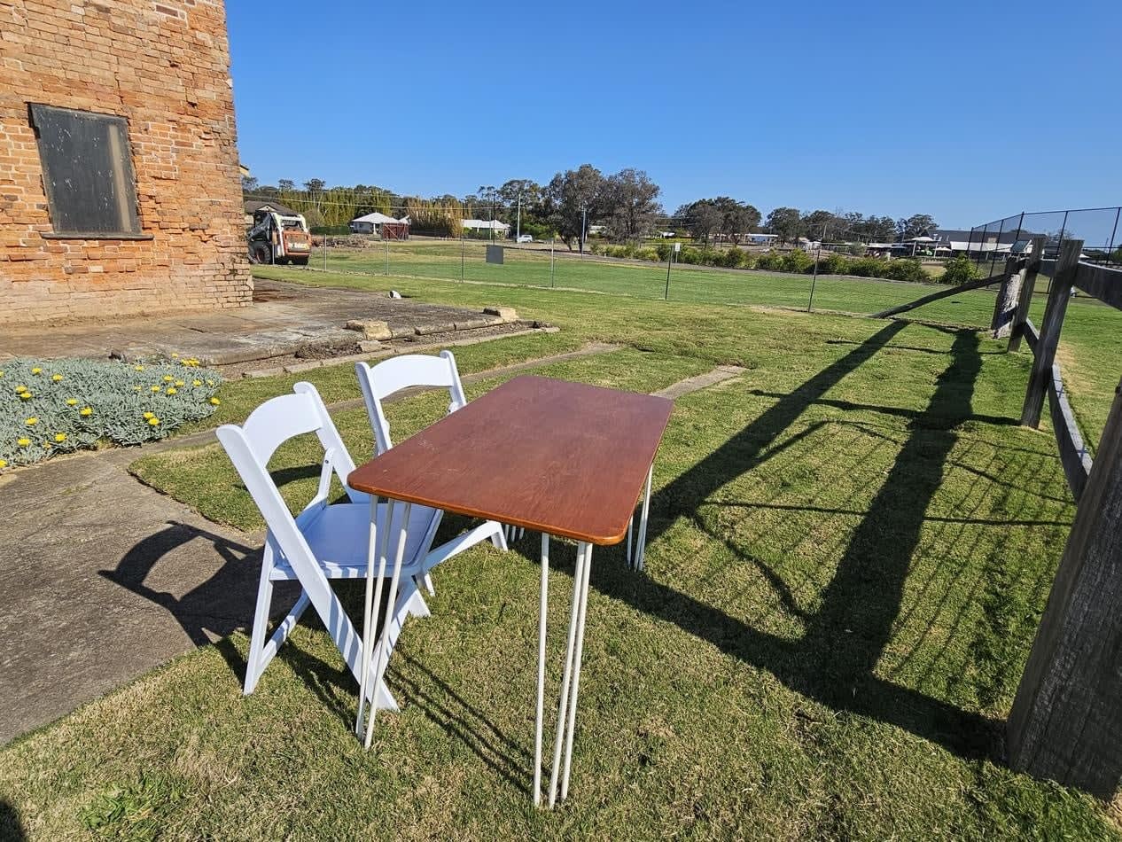 Two white chairs and a signing table in a grassy field.