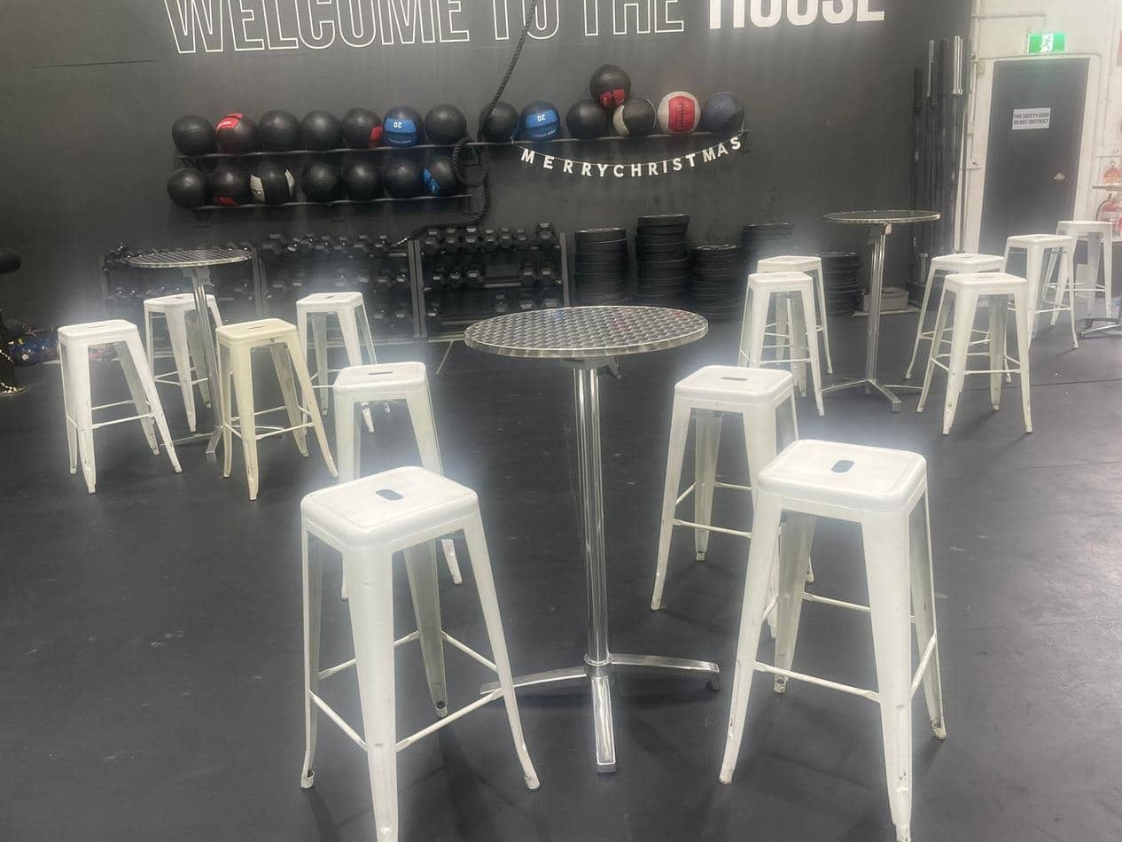 A group of stainless steel cocktail bar tables in a gym.