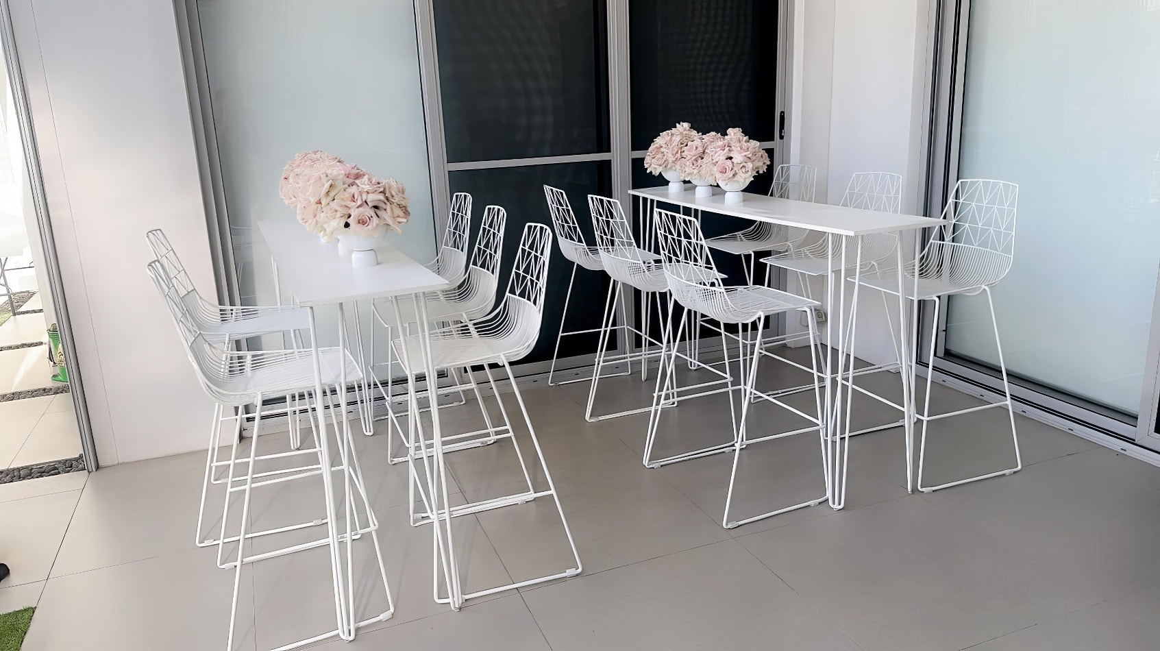 A set of white bar stools with flowers on them. High Bar Table w/ White Top Hire