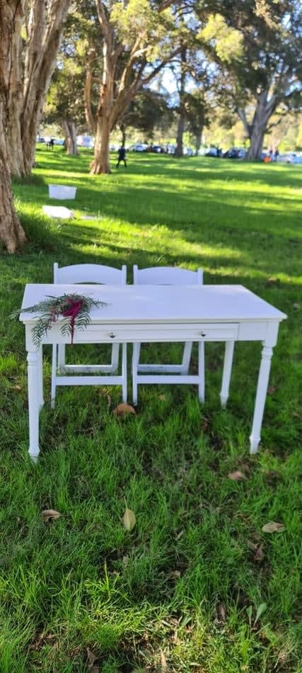 White vintage style table hire setup in a grassy area.