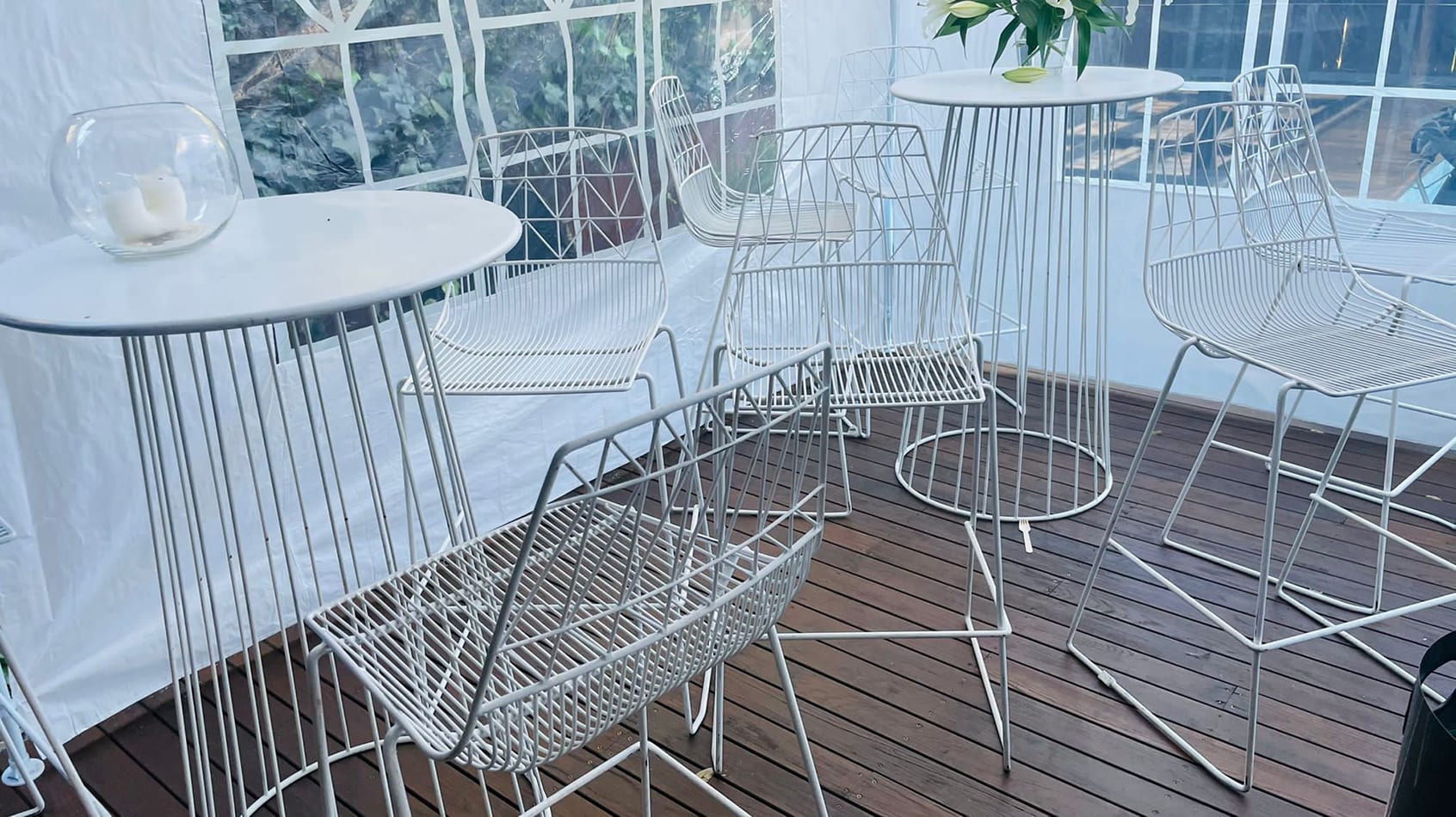 A white table and chairs on a wooden deck, perfect for your next cocktail party.