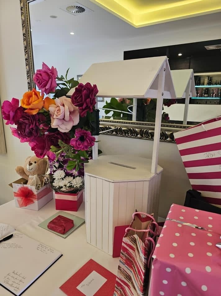 A table with pink flowers and gifts on it, perfect for your Wishing Well Hire event.