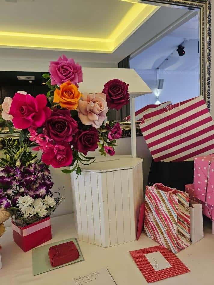 A table adorned with pink flowers and gift boxes, perfect for your Wishing Well Hire event.