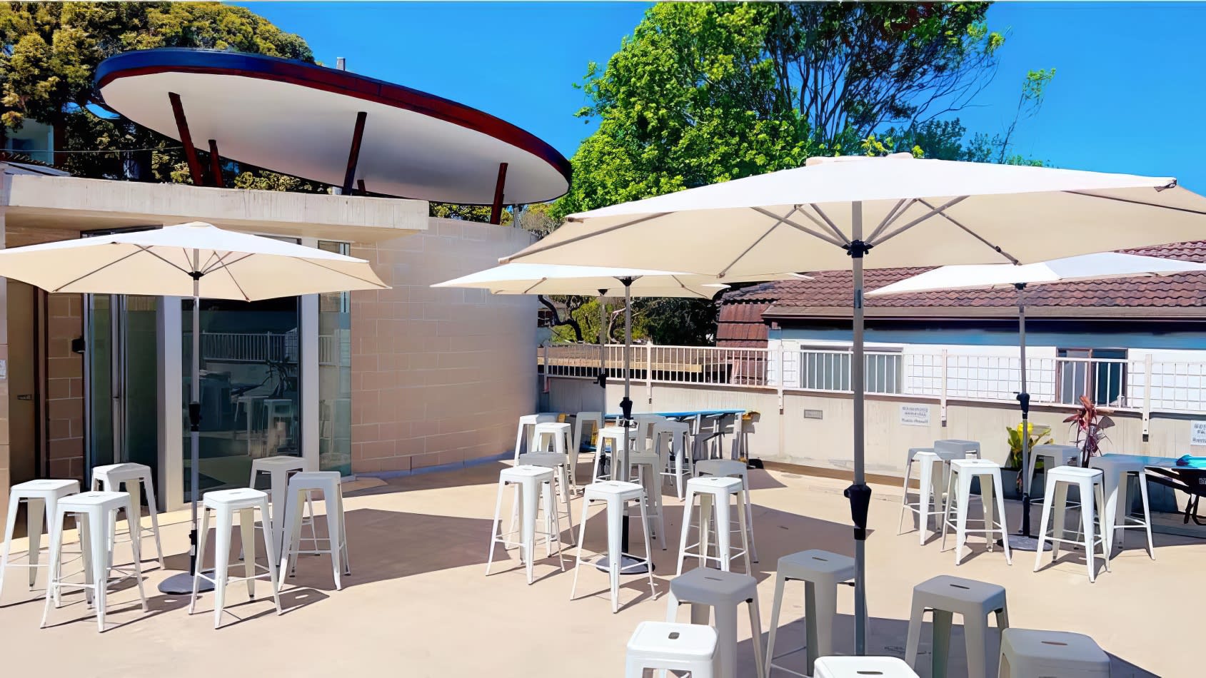 A patio with white market umbrellas and stools available for hire.