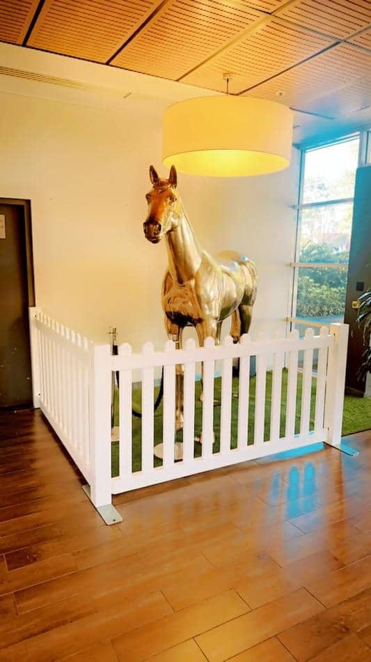 A horse statue in an office with a white picket fence available for hire.