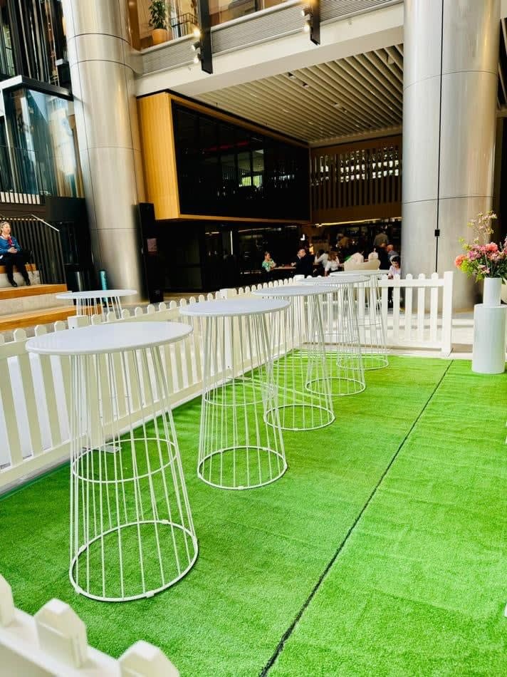 A white table and chairs set on a lush green grass lawn, creating a serene outdoor oasis within a building.