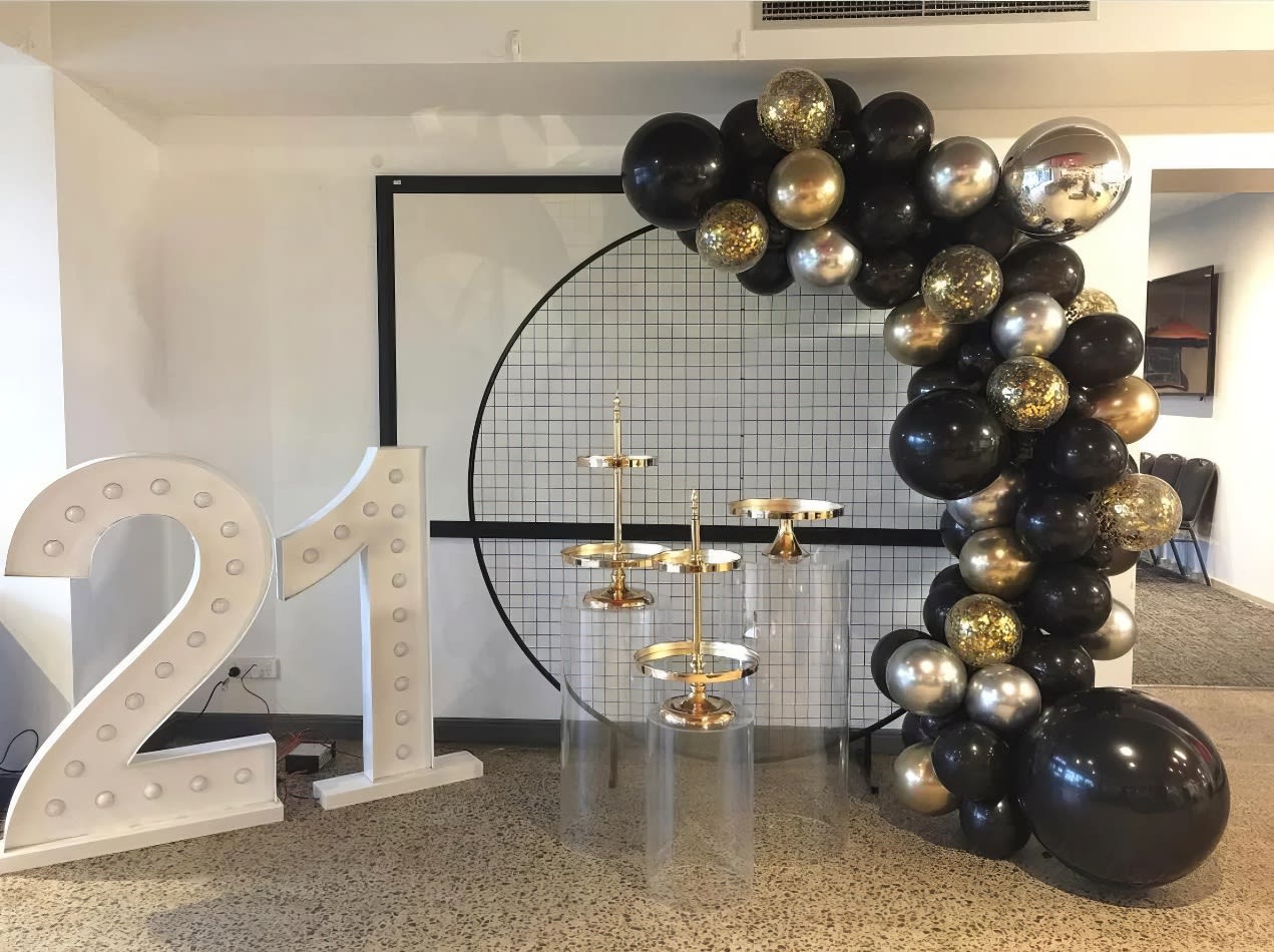 A circular balloon arch decorated with black and gold balloons.