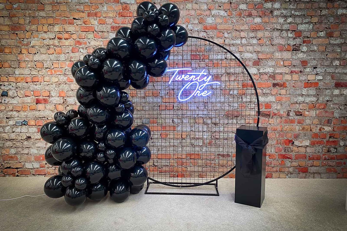 A black balloon arch with a circular black mesh backdrop hire.