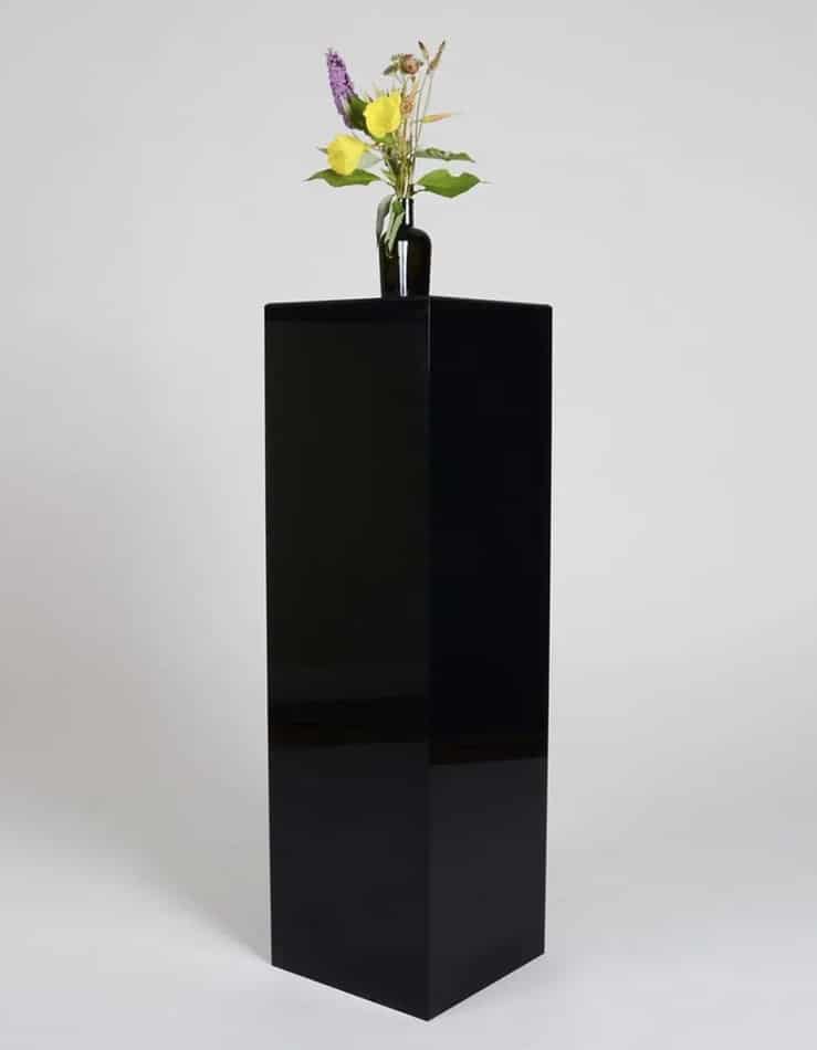 A large black vase stands on top of a square plinth.