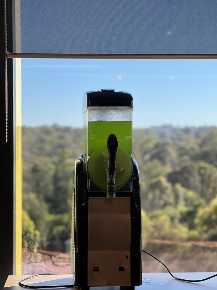 A green juice machine sitting in front of a window, offering 60 drinks.