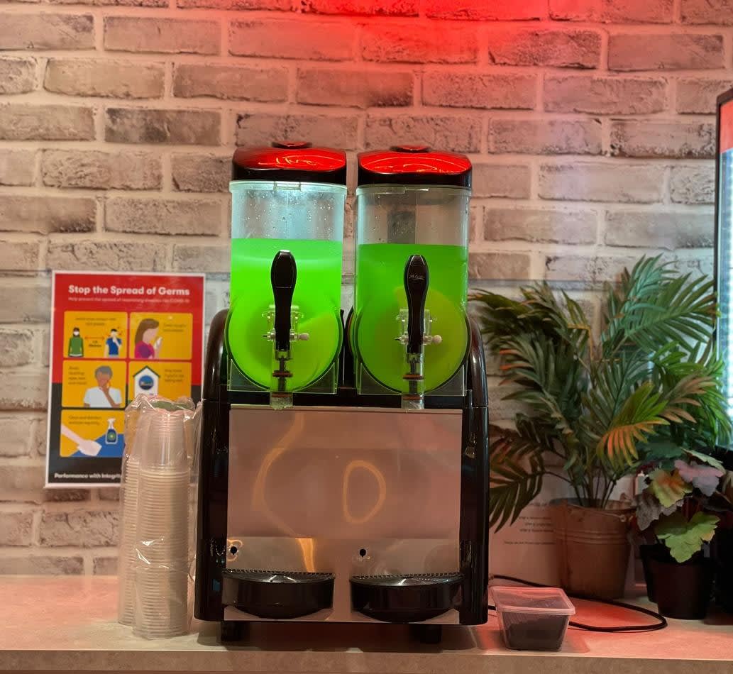 A Slushie Machine with package 2, featuring *120 Drinks*, and two green drinks on it.