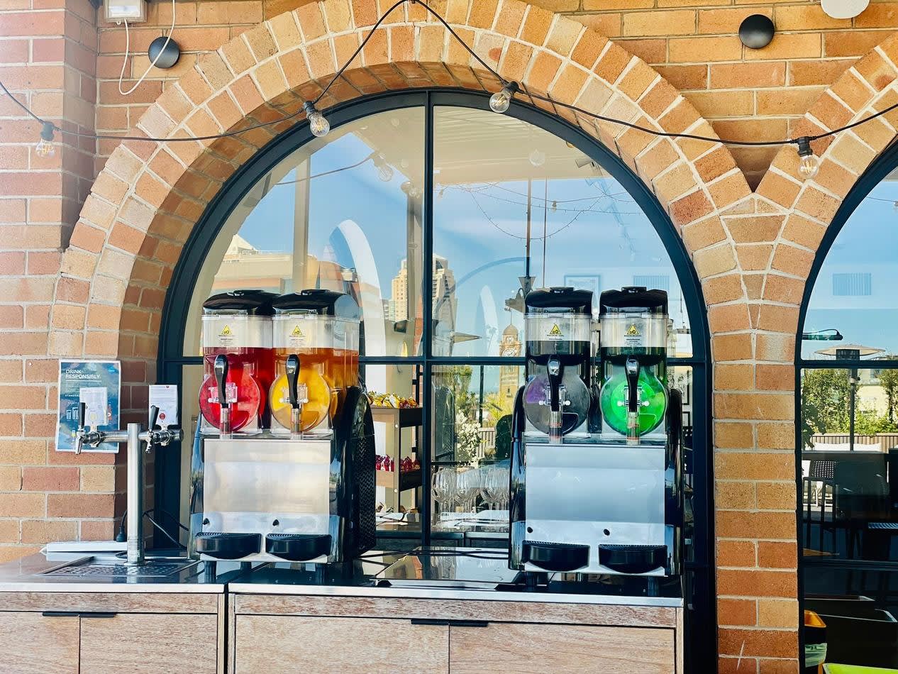 A Slushie Machine in front of a brick building, offering an impressive package of 240 drinks.