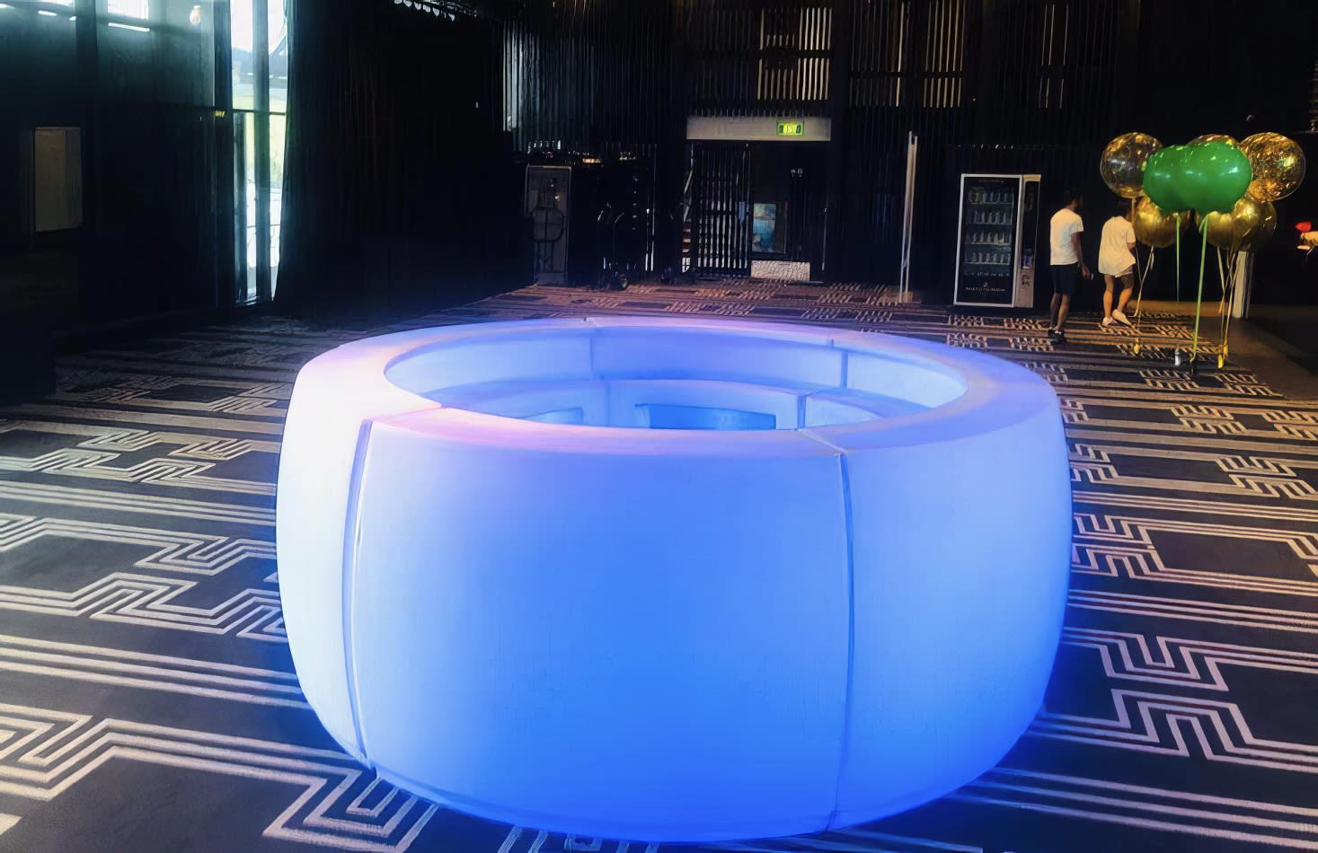 A blue LED circular table sitting on a carpeted floor, available for curved glow bar hire.